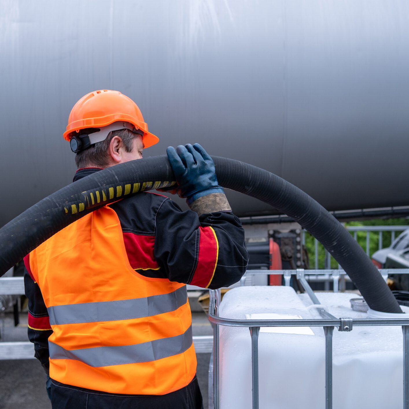 A technician transfers oil from a tanker into a 1000-liter IBC Bulk Container.