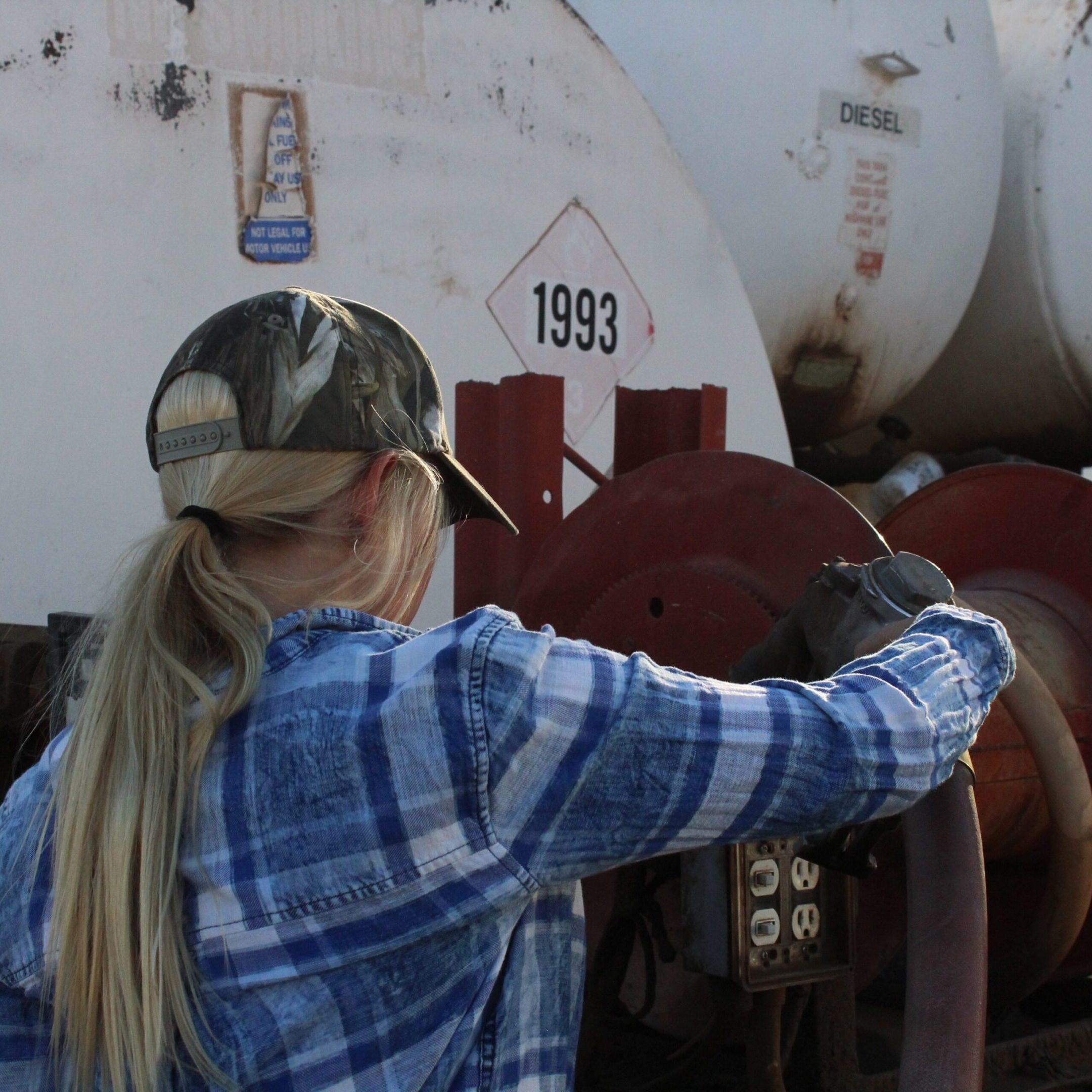 Worker operating hose at diesel storage tanks
